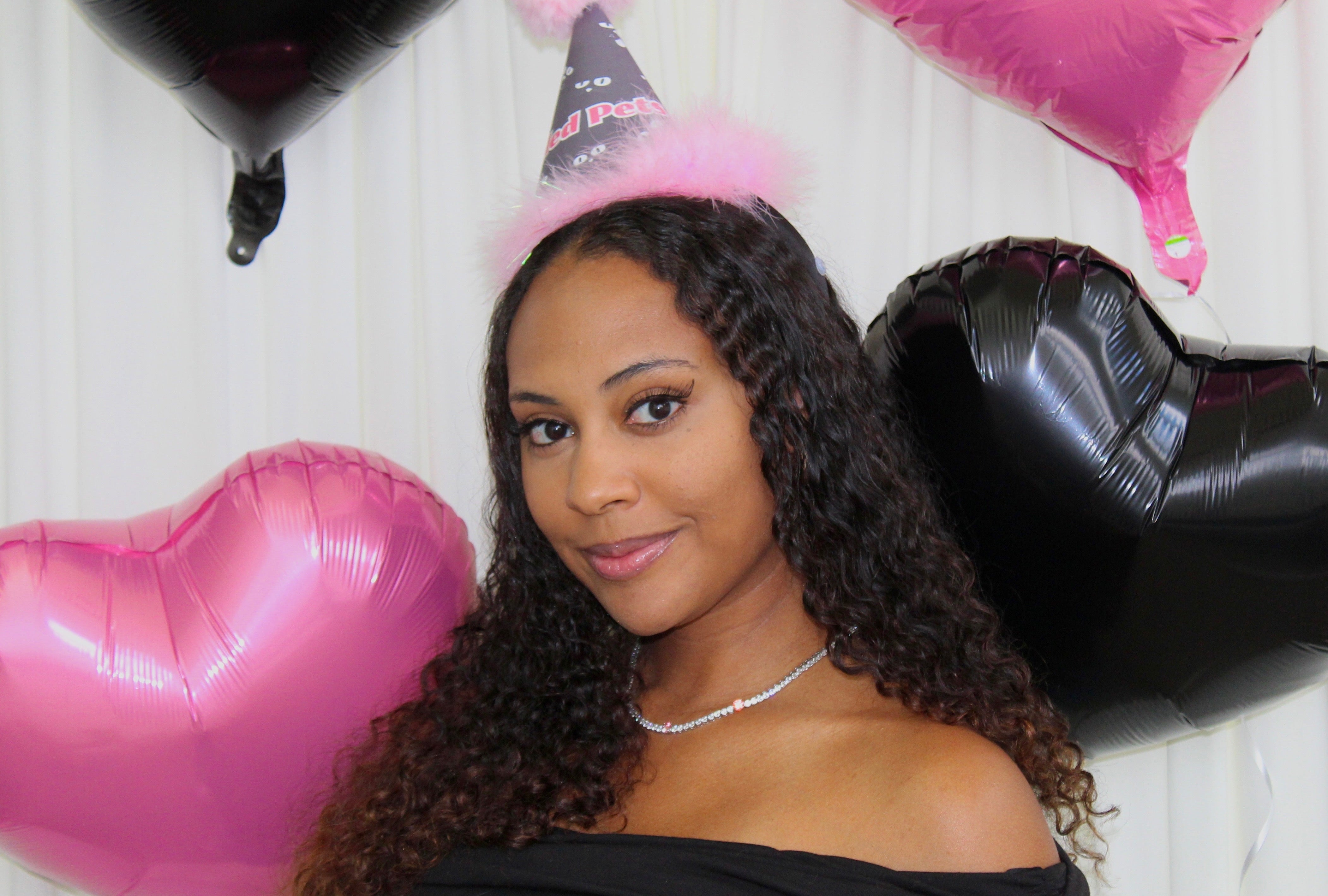 Woman wearing a party hat with balloons in the background